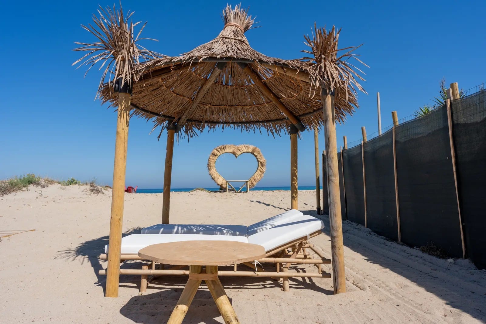 Gazebo in palma e lettini sulla sabbia del Dune Beach, con il mare sullo sfondo